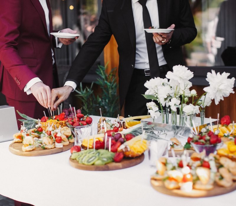 Close up of people serving themselves with fruits in buffet of restaurant